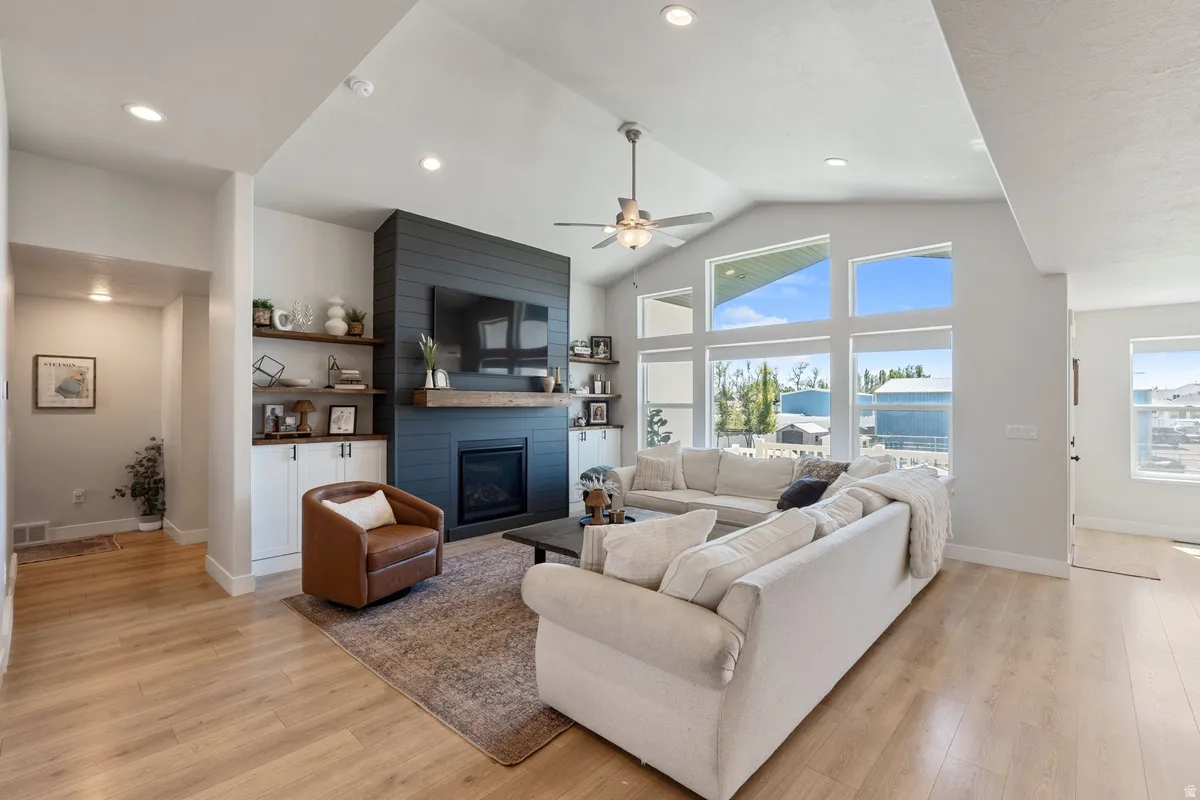 Vaulted ceilings, wood-finish flooring, and a contemporary fireplace with a wood mantle