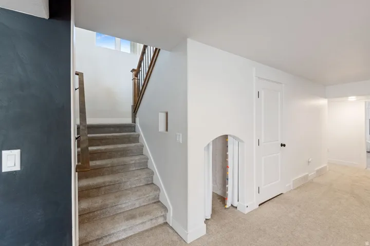 Carpeted staircase with dark wood and black metal balusters