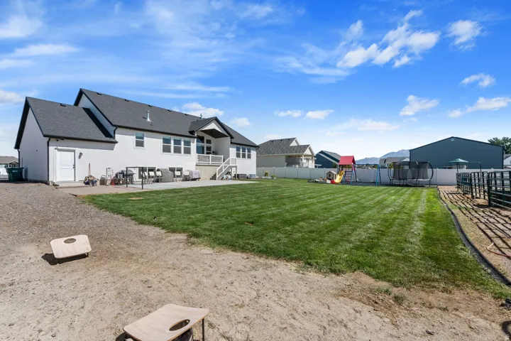 Expansive backyard with a manicured lawn, white privacy fencing, and a gravel area