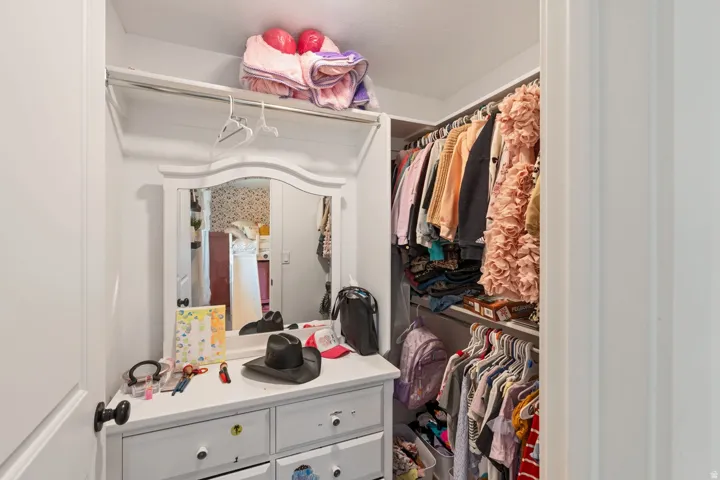 Walk-in closet with built-in shelving, hanging rods, and an integrated dressing vanity featuring a mirror