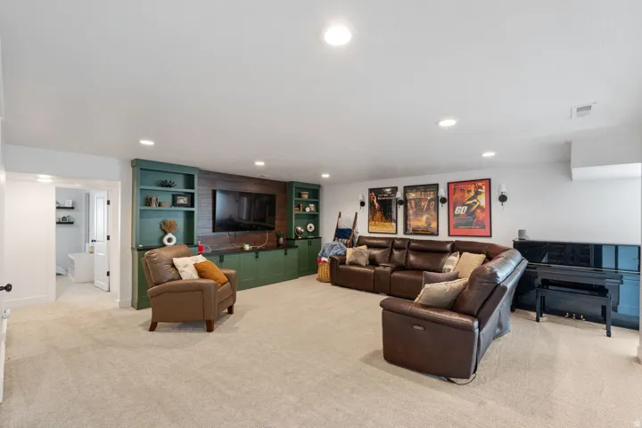 Built-in shelving with integrated cabinetry, recessed lighting, and soft carpet flooring