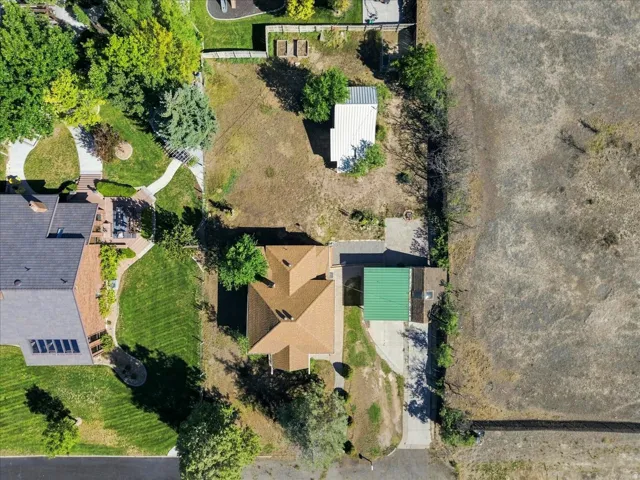 Property featuring a main residence with a brown shingle roof, an attached carport with a green metal roof, and an additional white accessory structure