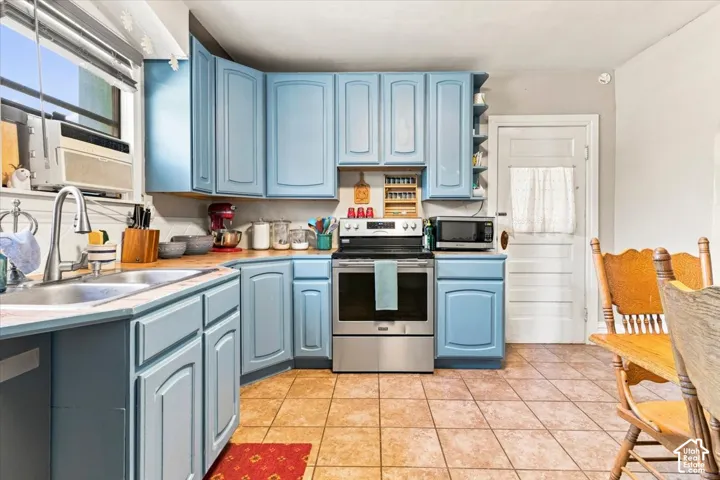 Kitchen featuring blue cabinetry, wood-finish countertops, stainless steel appliances, and tile flooring