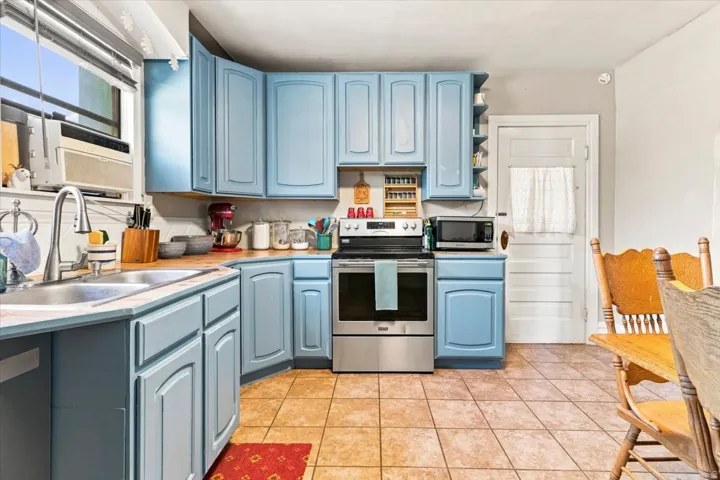 Kitchen featuring blue cabinetry, wood-finish countertops, stainless steel appliances, and tile flooring