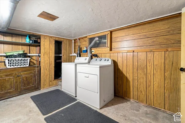 Utility area featuring wood-finish paneling, concrete flooring, and an exposed ceiling duct