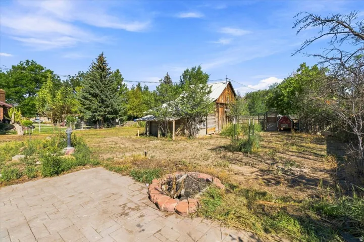 Expansive outdoor space featuring a paved patio, brick-ringed fire pit, and a rustic wood-sided outbuilding