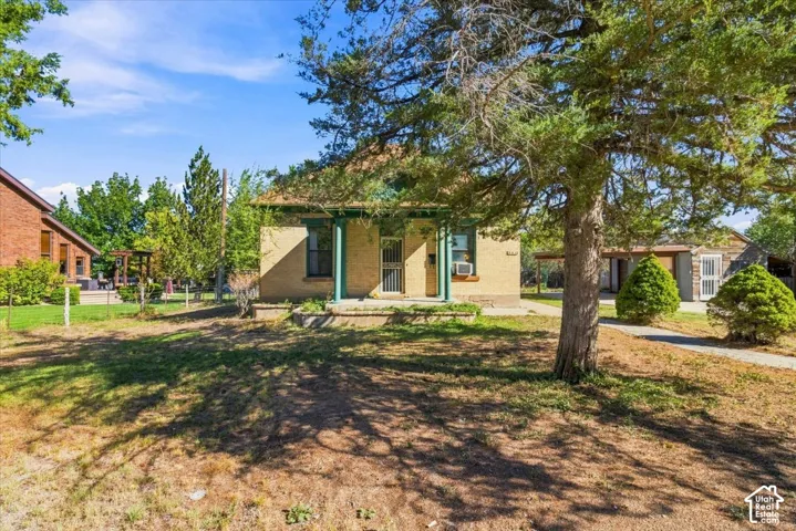 Stucco exterior with a covered front porch and mature trees