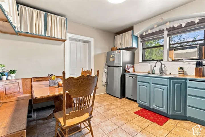 Kitchen featuring blue cabinetry, a stainless steel refrigerator, and wood-finish countertops