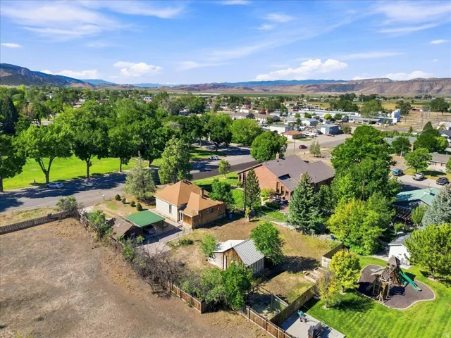 Expansive property featuring multiple structures, mature trees, and mountainous surroundings