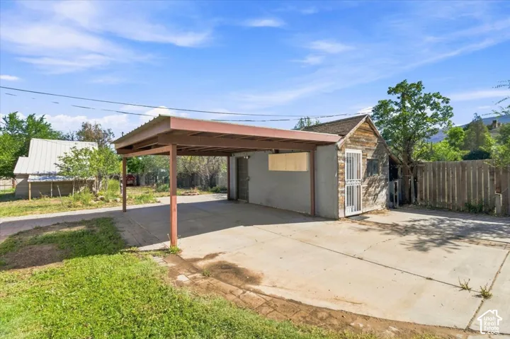 Concrete driveway with an attached carport featuring a metal roof