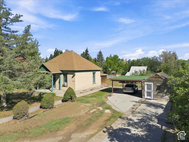 Single-story residence featuring a covered front porch with columns, a detached carport, and a separate wooden outbuilding