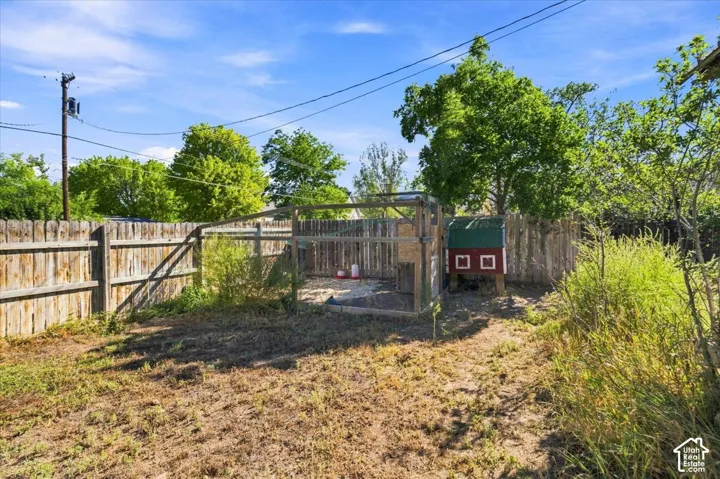 Fenced backyard featuring a built chicken coop and natural landscaping