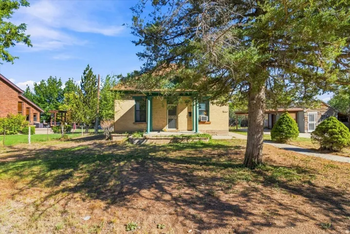Stucco exterior with a covered front porch and mature trees