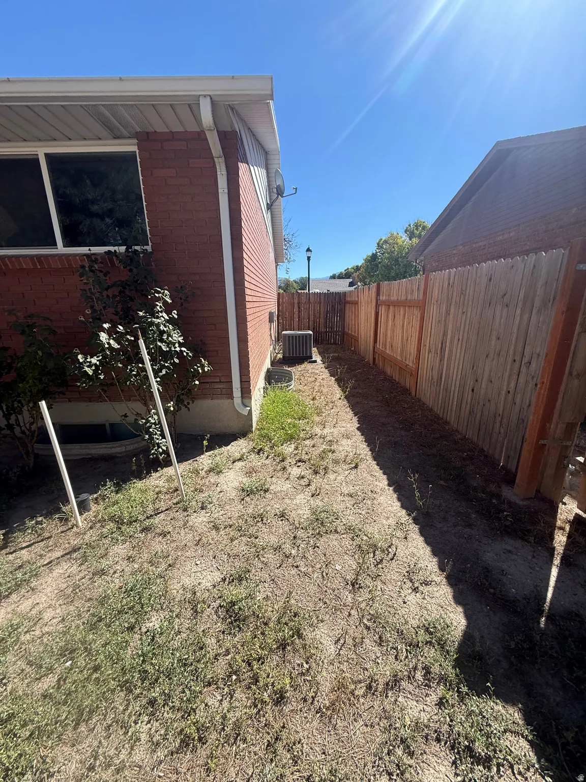 Brick exterior with white soffit, wood fencing, and an outdoor HVAC unit