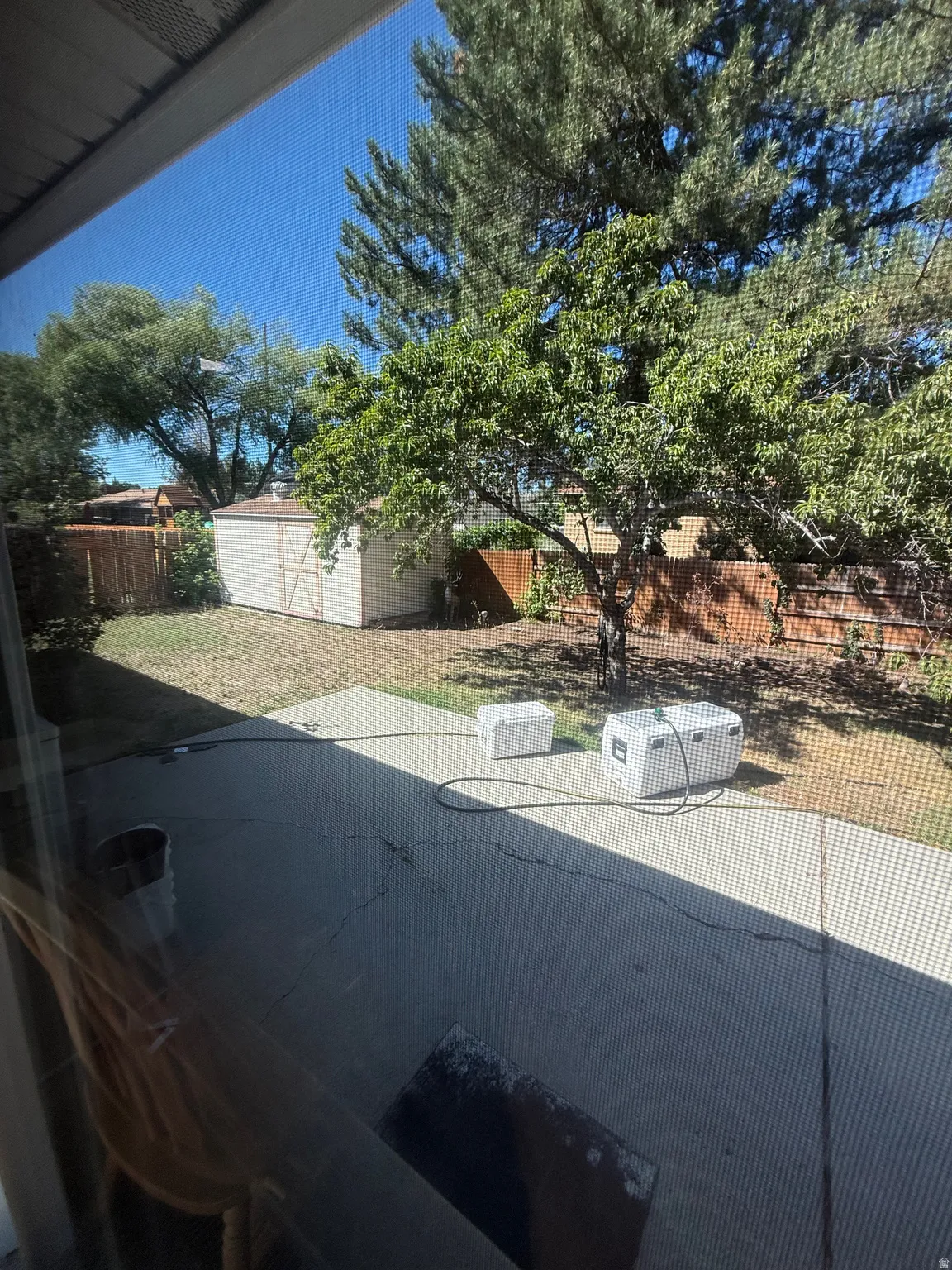 Back yard with patio area and storage shed in the background.