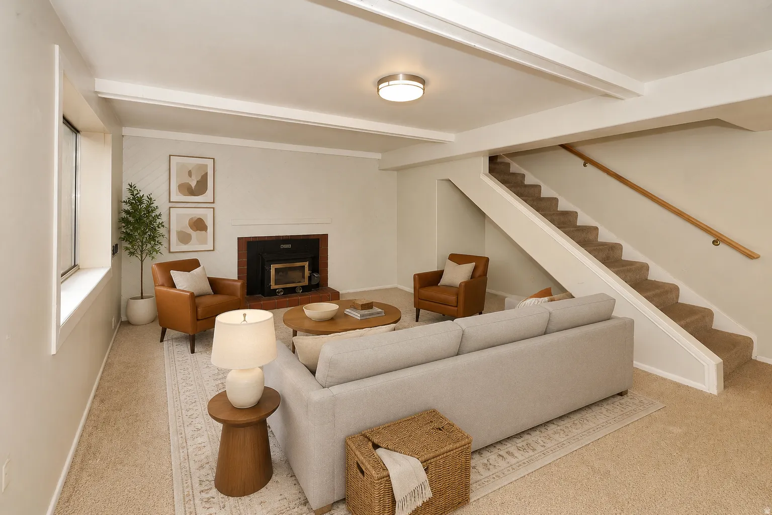 Side A basement Living area with exposed ceiling beams, carpeted flooring, a fireplace with a dark surround, and a carpeted staircase with a wood handrail