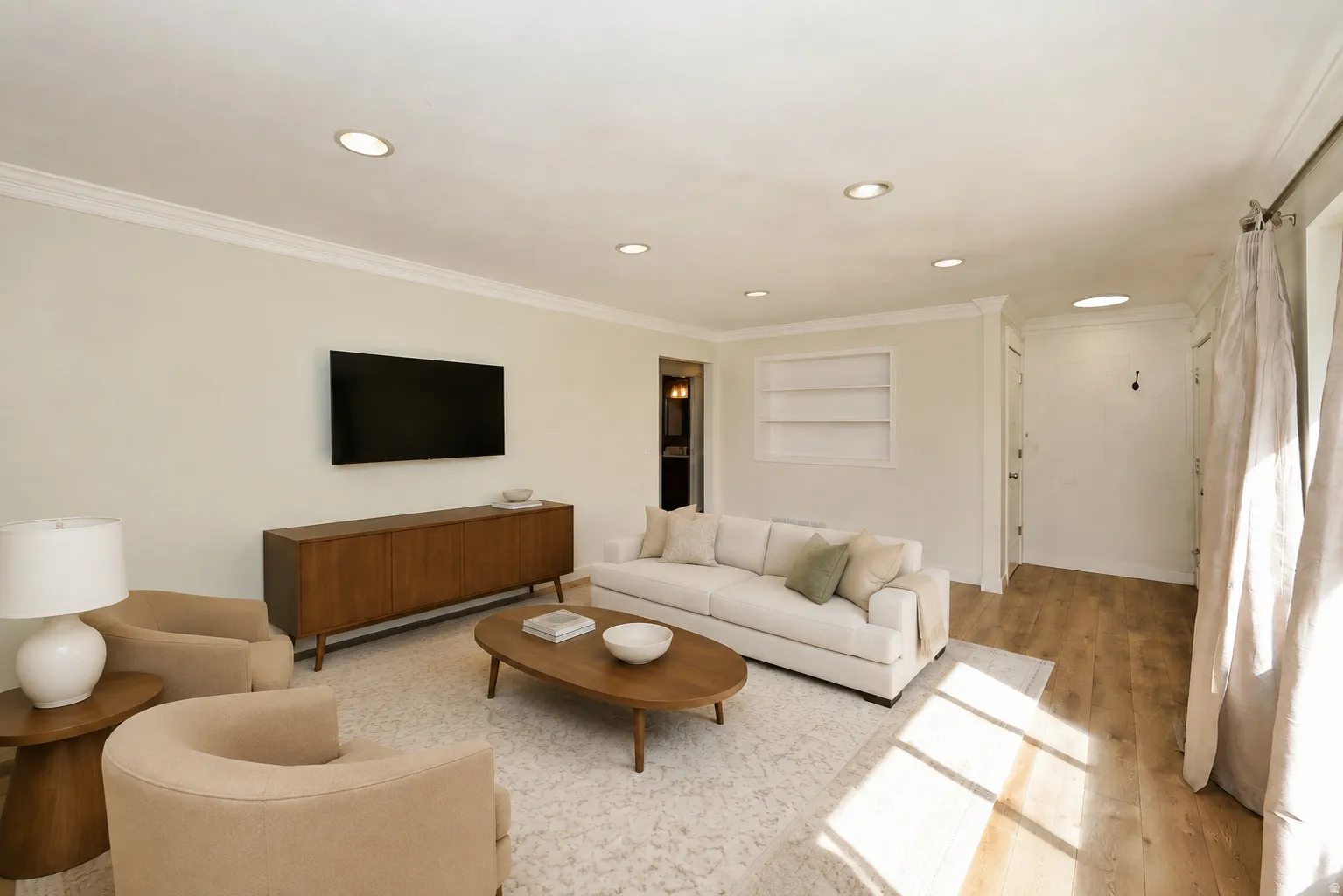 Side A living room. Recessed ceiling lighting, crown molding, built-in shelving, and wood-finish flooring