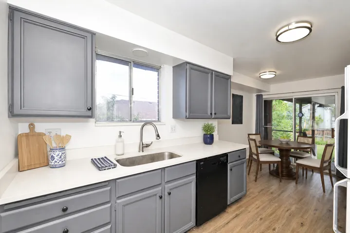 Side B Kitchen featuring gray cabinetry, white countertops, stainless steel sink, wood-finish flooring, and a sliding glass door