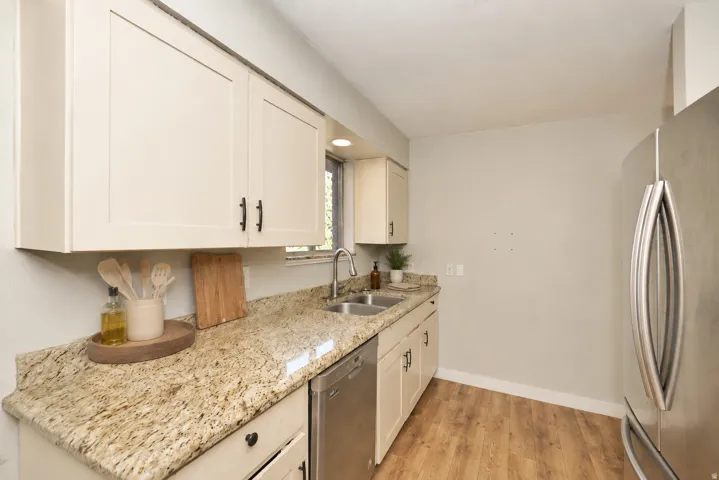 Side A Kitchen featuring wood-finish flooring, light-toned cabinetry, stainless steel sink, and light-colored countertops