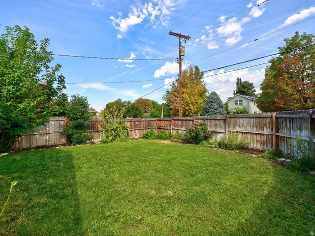 Side B private back yard. Expansive backyard featuring a green lawn, wood fence, and mature perimeter trees