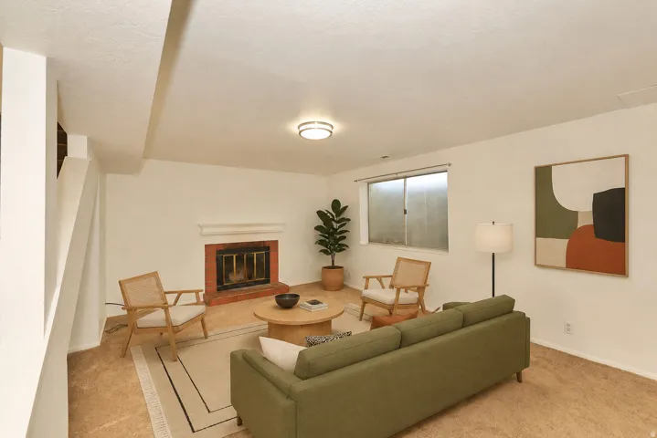 Side B basement living room. Recessed fireplace with a brick hearth, wall-mounted light fixture, and a window