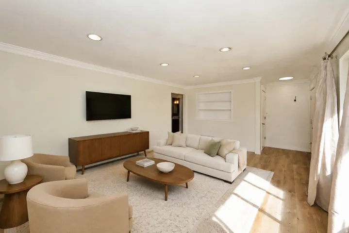 Side A living room. Recessed ceiling lighting, crown molding, built-in shelving, and wood-finish flooring