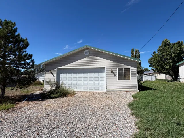 Detached garage featuring panel siding, a panel garage door, a side window, and a gravel driveway