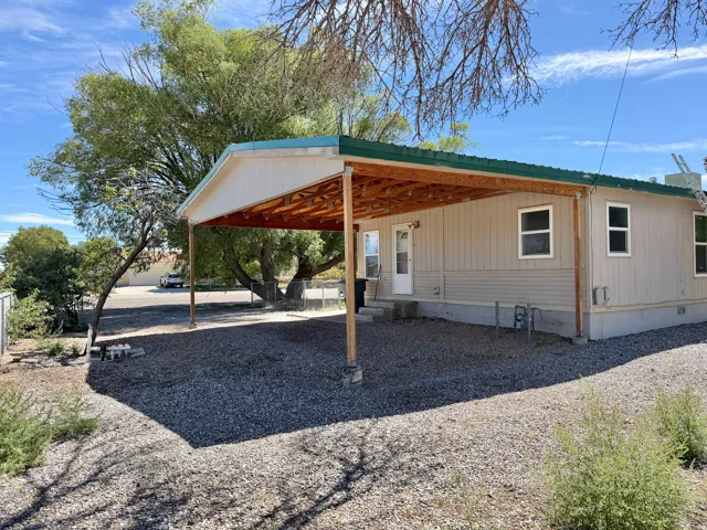 Attached covered patio with exposed wood ceiling, gravel landscaping, exterior siding, and a metal roof
