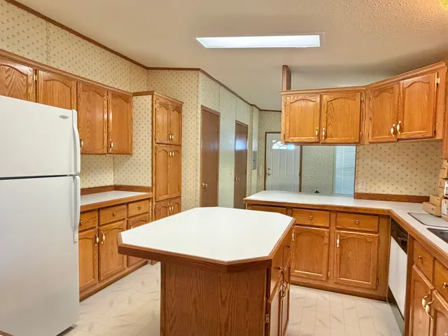 Kitchen featuring wood cabinetry, white countertops, a central island, and vinyl flooring