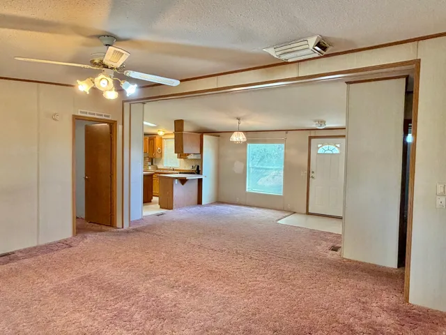 Open concept living area with carpet flooring, ceiling fan, and decorative light fixture