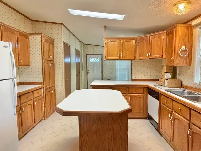 Kitchen featuring wood-finish cabinetry, a central island with white countertops, and a double basin sink