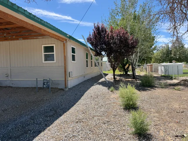 Exterior siding with multiple windows, gravel ground cover, and mature trees