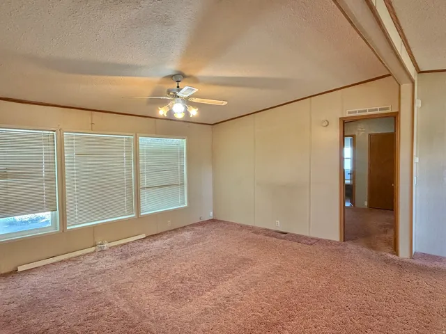Ceiling fan with light fixture, multiple windows, wall paneling, and carpeted flooring