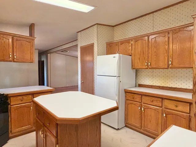 Kitchen featuring wood cabinetry, a central island with a solid surface countertop, and built-in appliances