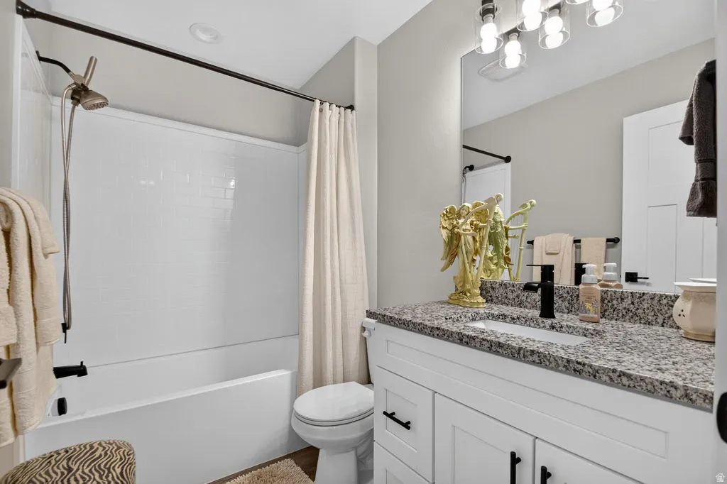 White vanity with black hardware, granite-style countertop, and rectangular undermount sink