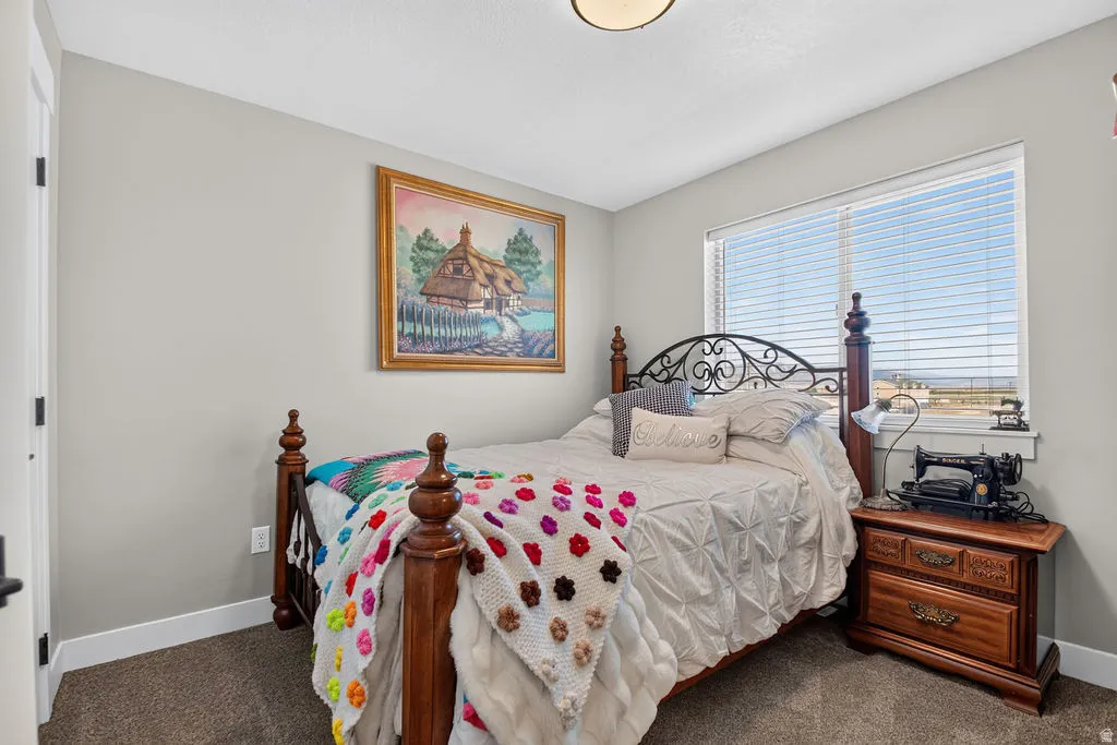 Bedroom with carpet flooring, neutral wall tones, and a window with horizontal blinds