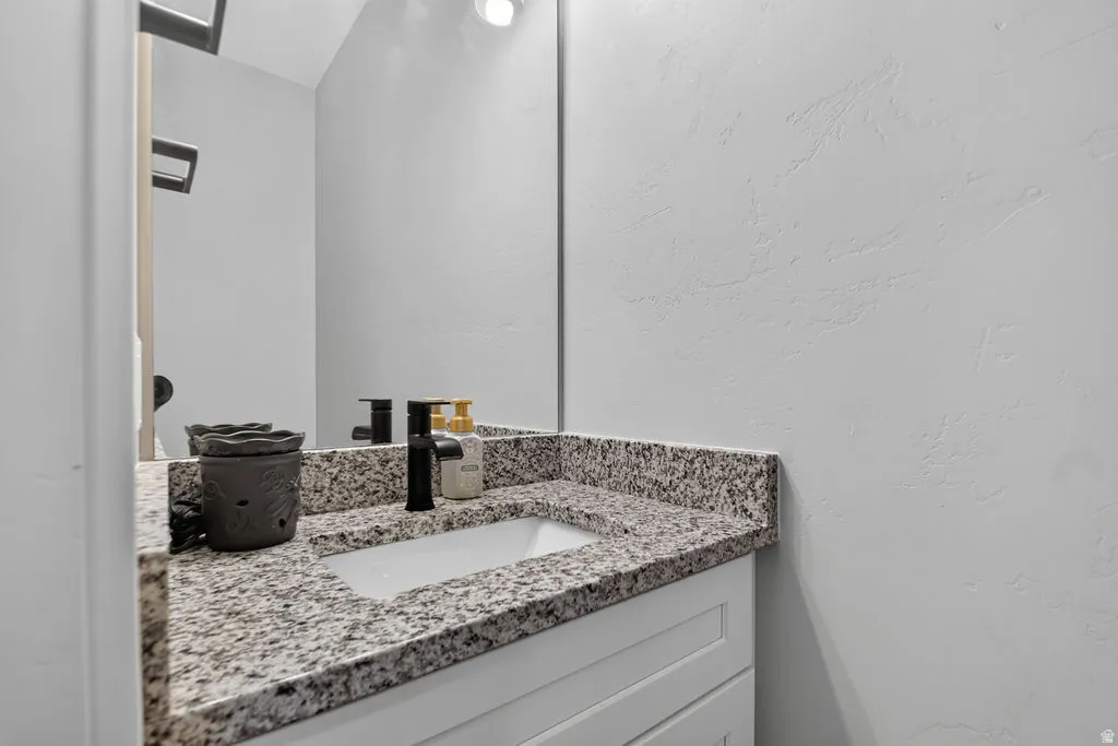 Vanity with a granite countertop, undermount sink, and matte black faucet