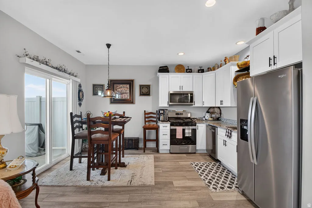 Kitchen featuring white cabinetry, stainless steel appliances, and wood-finish flooring