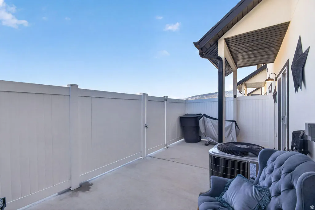 Poured concrete patio with white privacy fencing and gate, featuring a covered outdoor area with dark soffit and fascia
