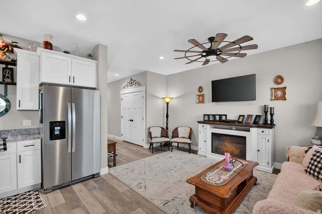 Stainless steel refrigerator, white cabinetry, wood-finish flooring, recessed lighting, and a ceiling fan with wood-look blades