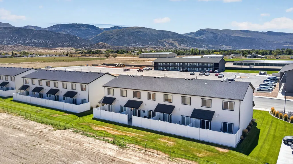 Modern townhouse exteriors with private patios, individual awnings, and white privacy fencing