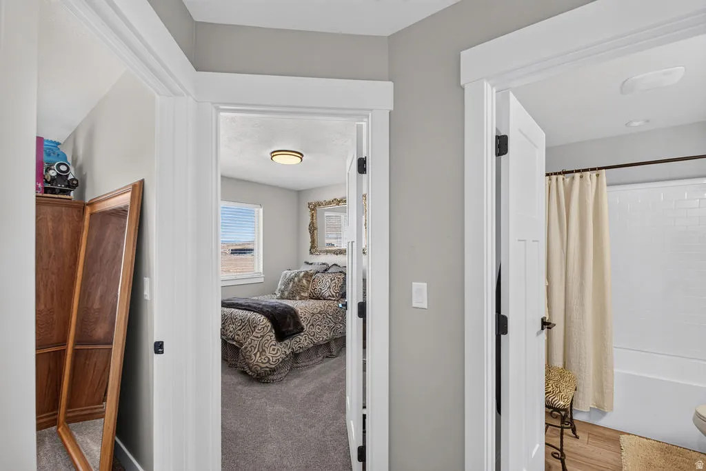 Hallway with neutral wall color, white trim, and doors with black hardware