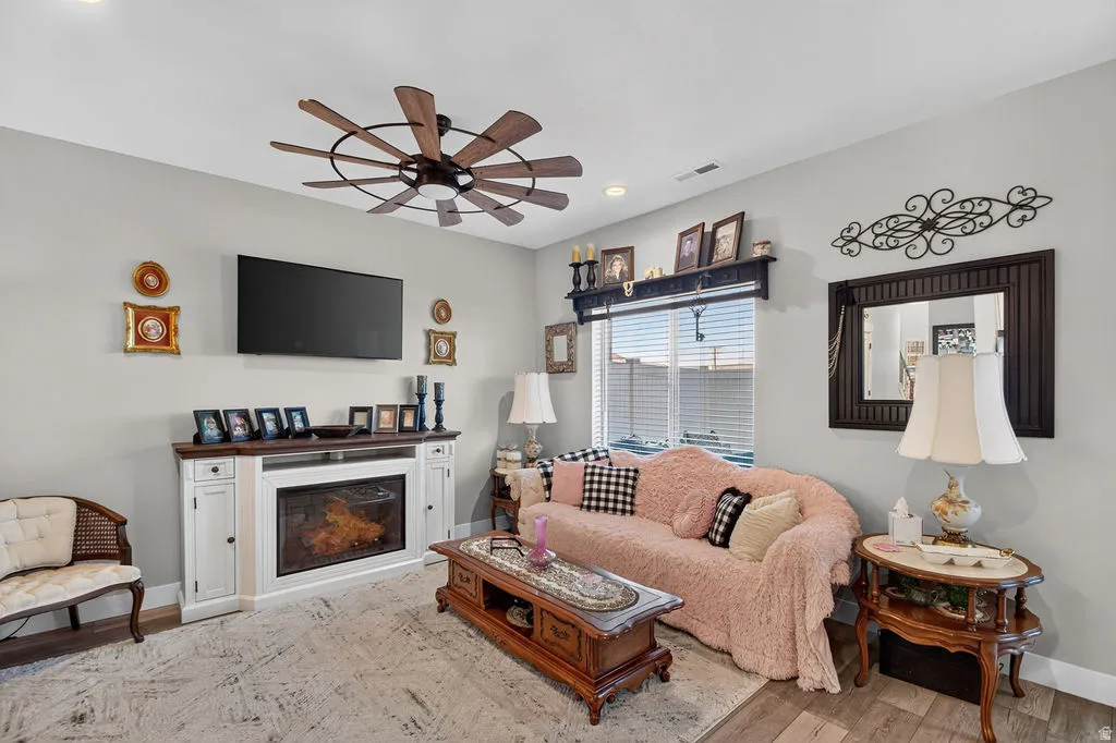 Living area with wood-finish flooring, a ceiling fan, and a built-in fireplace feature