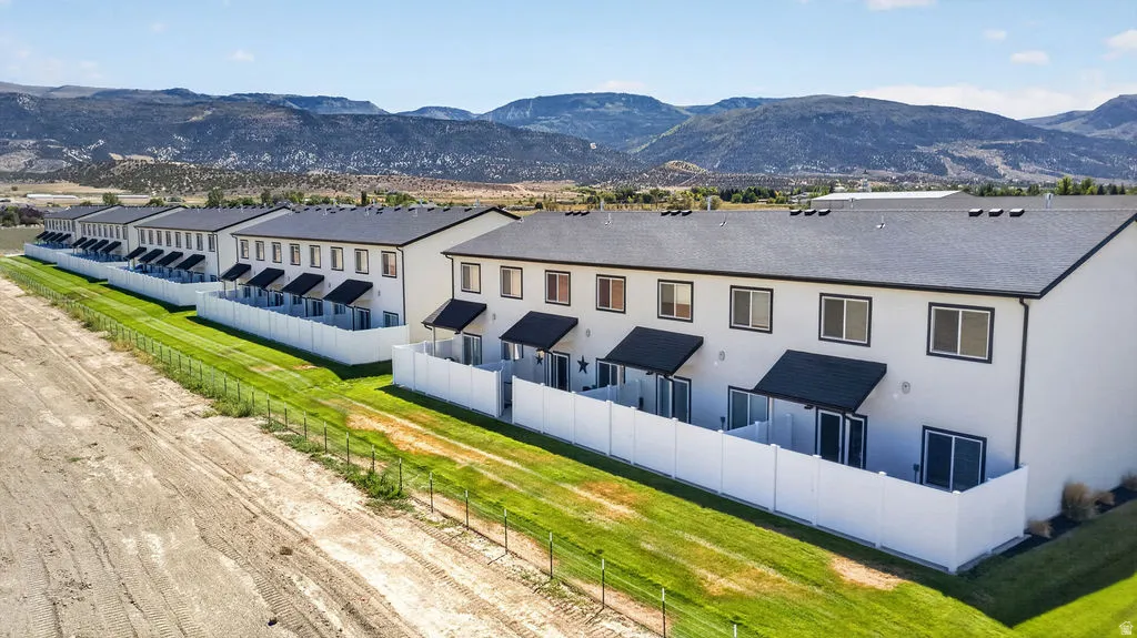 Row of contemporary townhomes featuring private patios, white privacy fencing, and dark shingle roofs