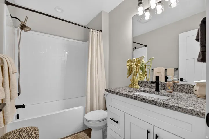 White vanity with black hardware, granite-style countertop, and rectangular undermount sink