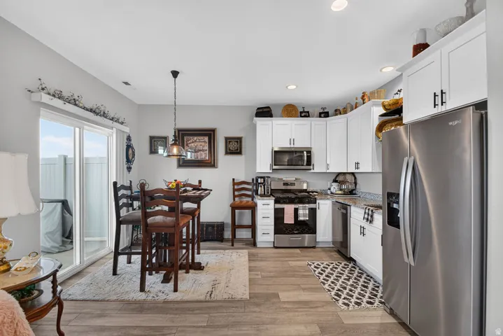 Kitchen featuring white cabinetry, stainless steel appliances, and wood-finish flooring