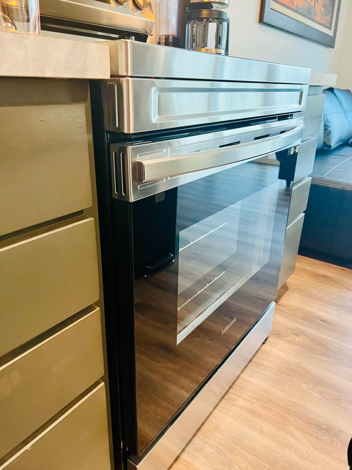 Stainless steel range with a glass oven door, wood-finish flooring, and minimalist cabinetry