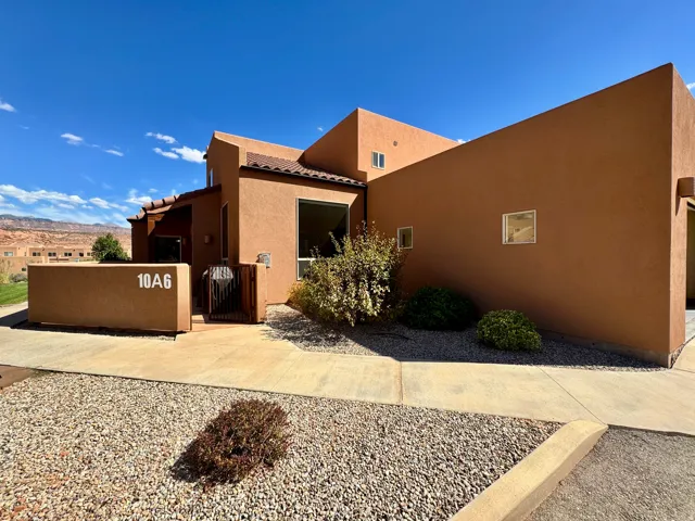 Terracotta stucco exterior with a flat roofline, integrated landscaping, and privacy wall