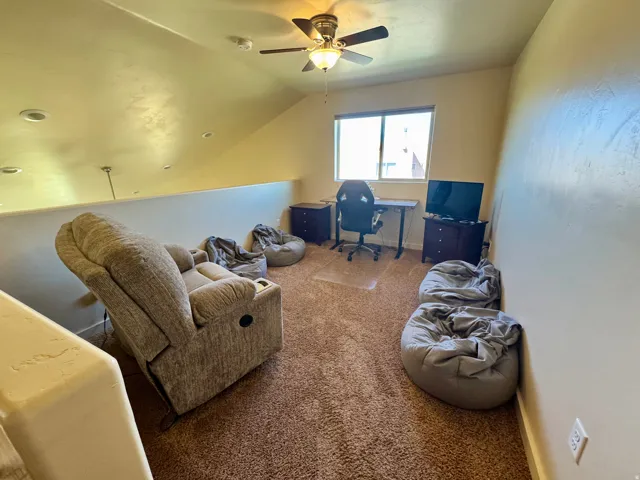 Carpeted loft space with a ceiling fan, recessed lighting, and a window
