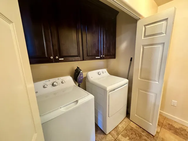 Laundry area featuring dark wood-finish cabinetry, tile flooring, and a white paneled door